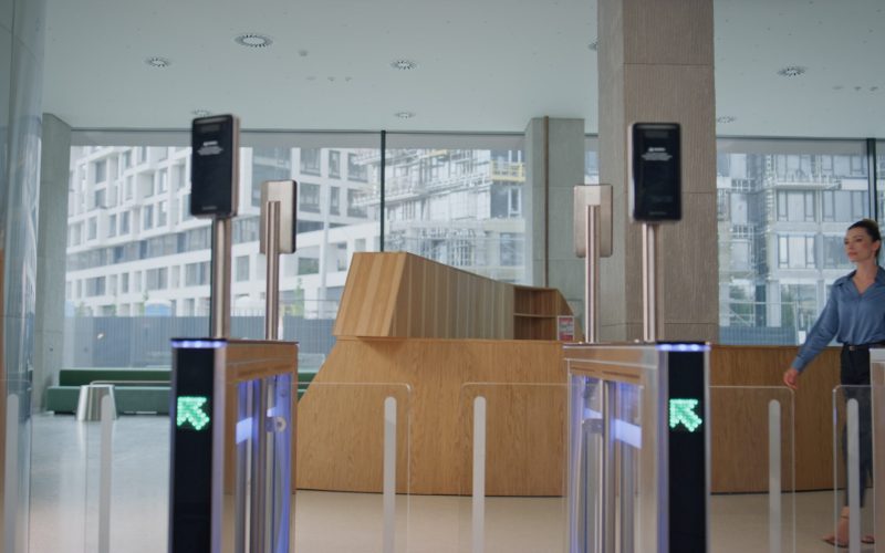 Confident businesswoman entering office turnstile starting workday. Elegant successful lady looking on screen for face id to pass security control. Female entrepreneur walking through electronic gates